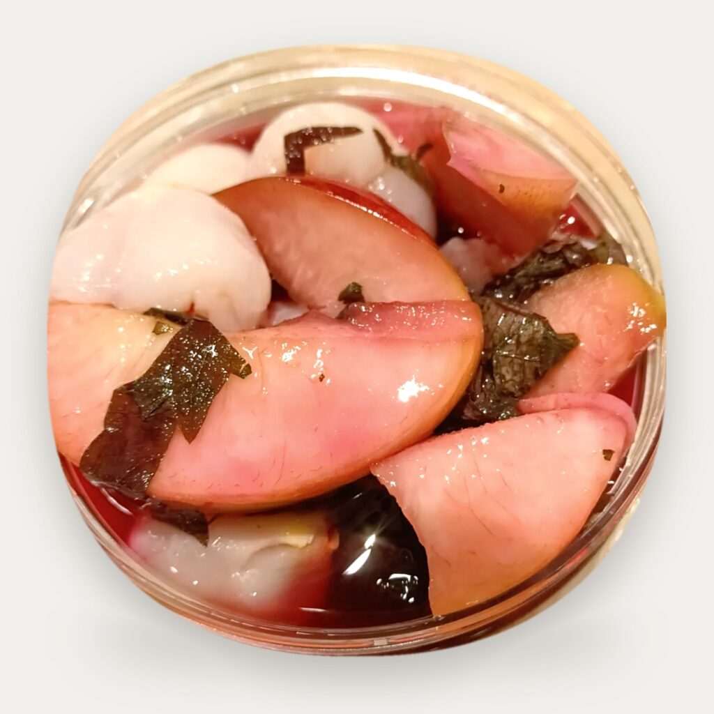 Frozen Perilla Peach: peach slices and perilla (shiso) leaves in red peach juice in a clear jar